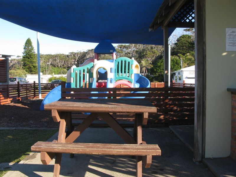 Blue Lagoon Beach Resort - Bateau Bay: Camp kitchen and BBQ area with playground in the background.