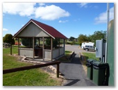 Waratah Caravan Park and Camping Ground - Waratah: Camp kitchen with motor home parking on gravel behind.