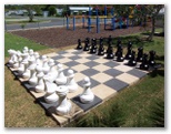 Yamba Waters Holiday Park - Yamba: Chess set with playground for children in the background
